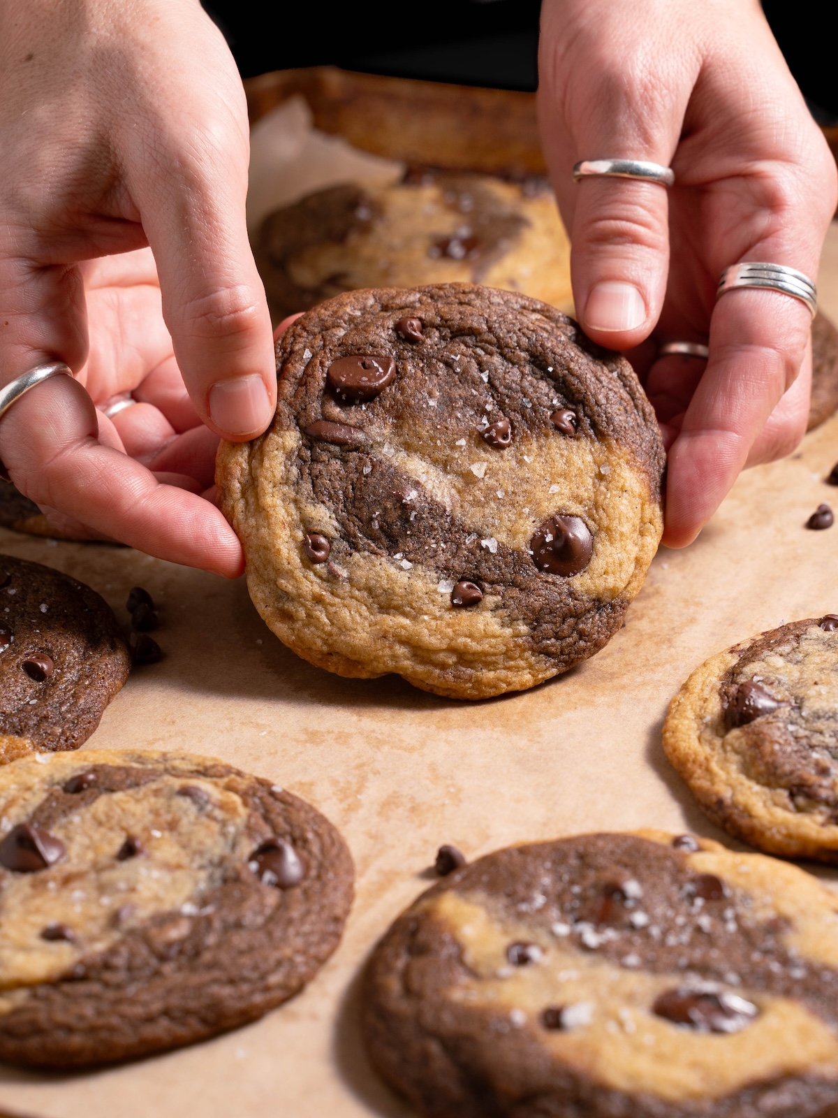 Hands holding a marbled chocolate and vanilla cookie