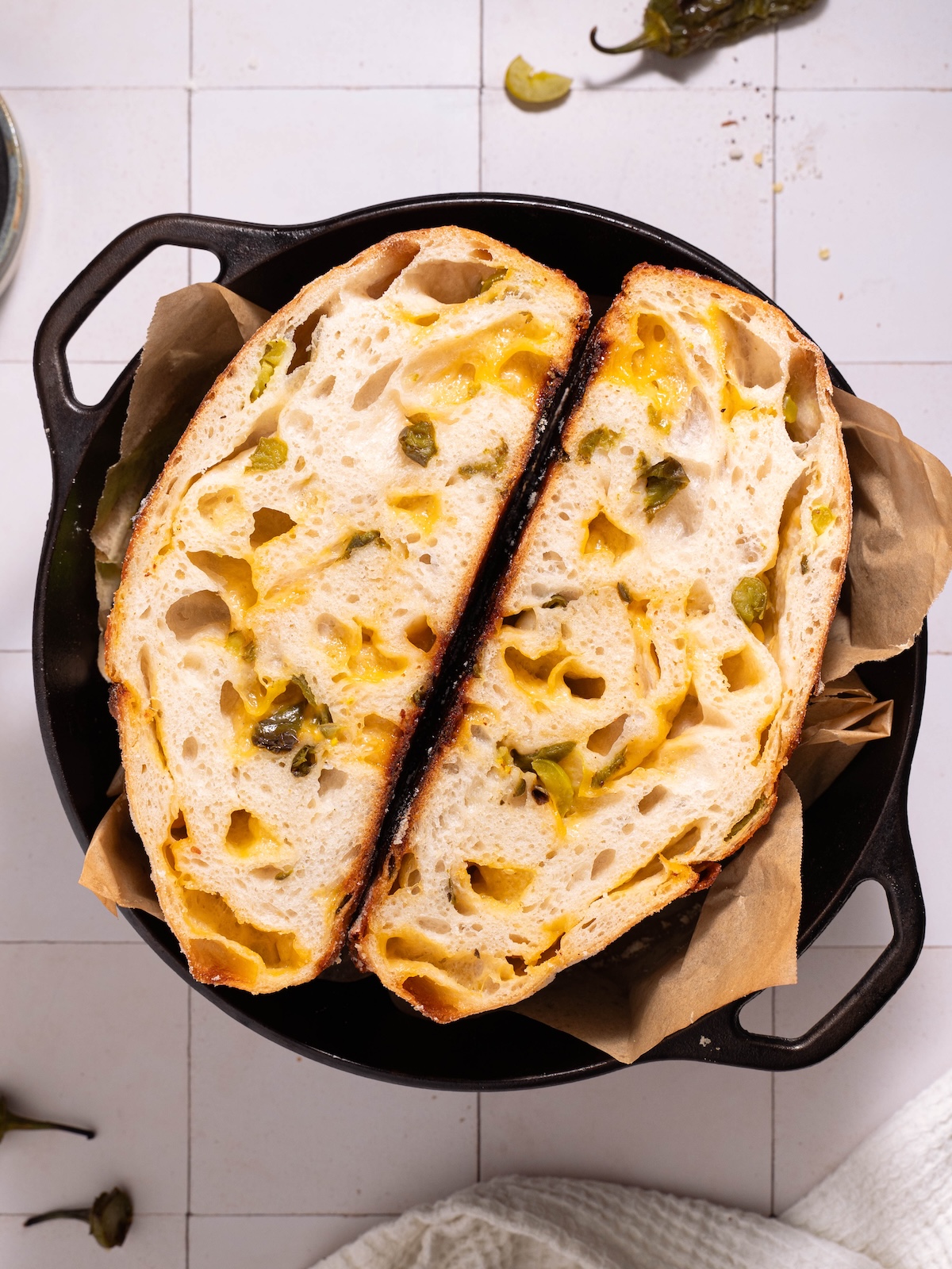 A loaf of homemade jalapeño cheddar sourdough sliced in half in a cast iron dutch oven