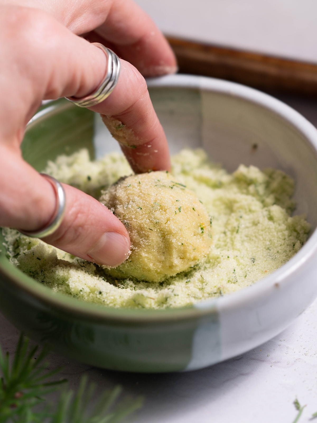 Rolling a cookie dough ball in pine needle sugar