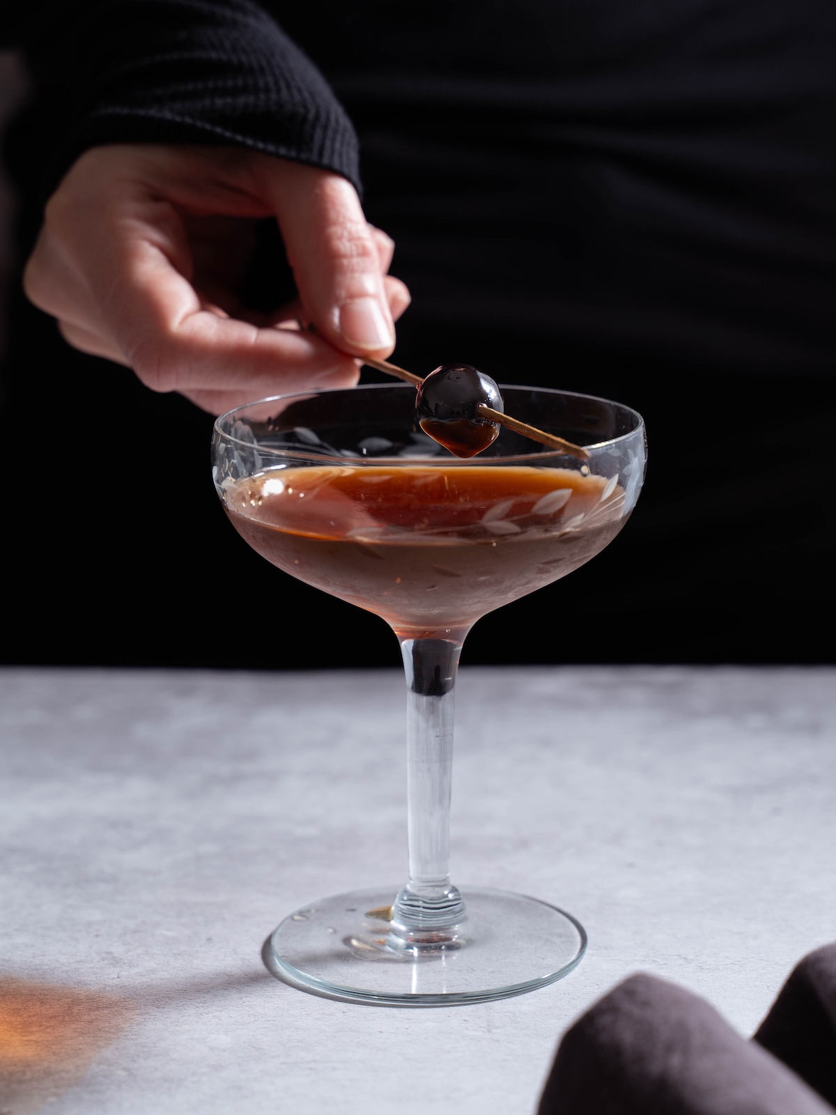 Adding a cherry garnish to a cocktail