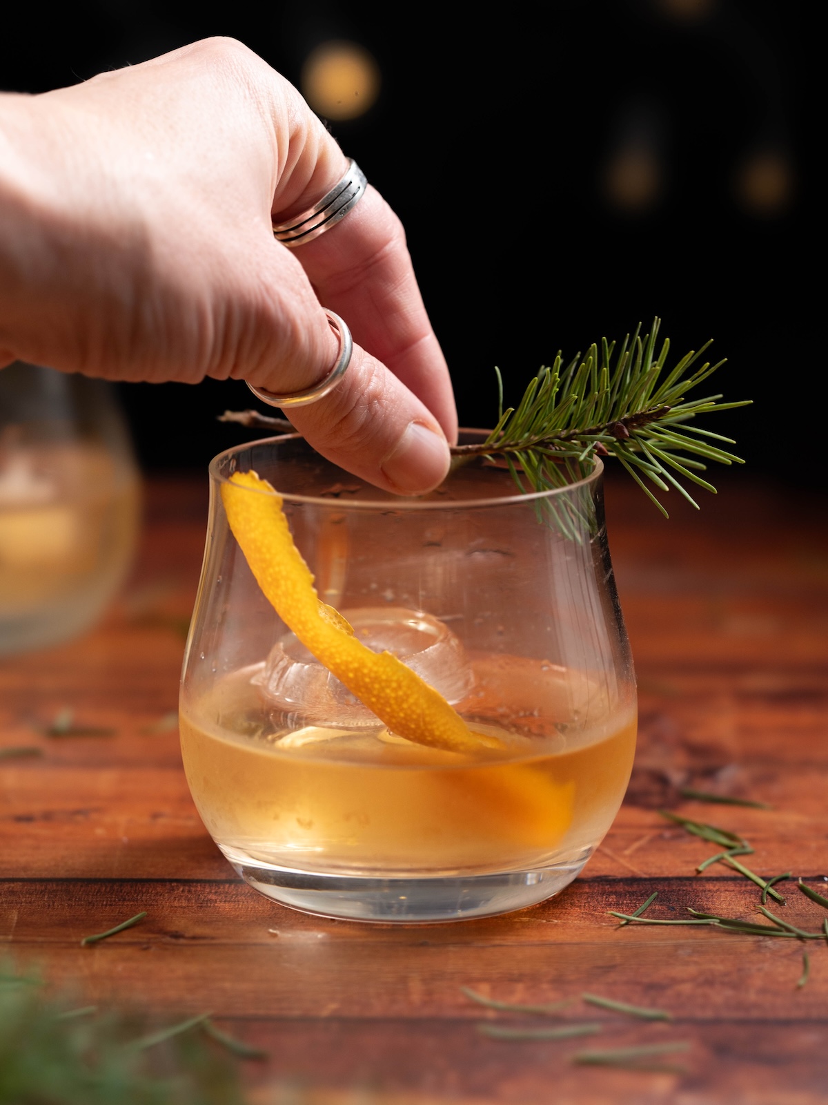 Garnishing a Pine Needle Old Fashioned with a Douglas fir twig