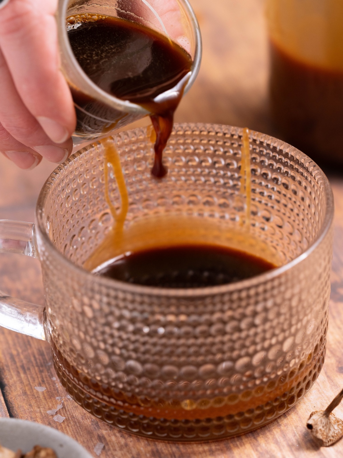 Pouring an espresso shot into a mug with caramel
