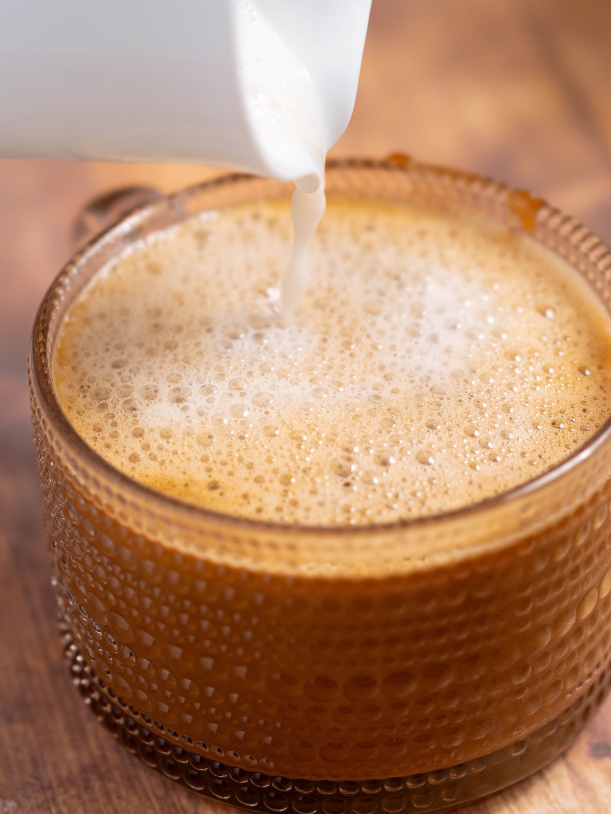 Pouring frothed milk into a homemade latte