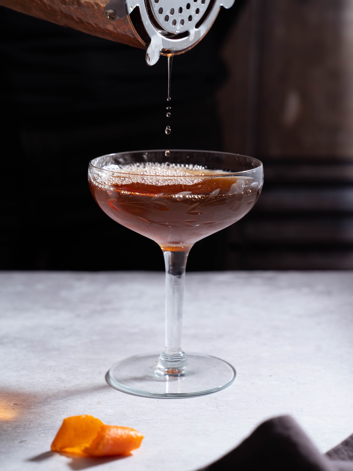 Pouring a Black Manhatten out of a cocktail shaker