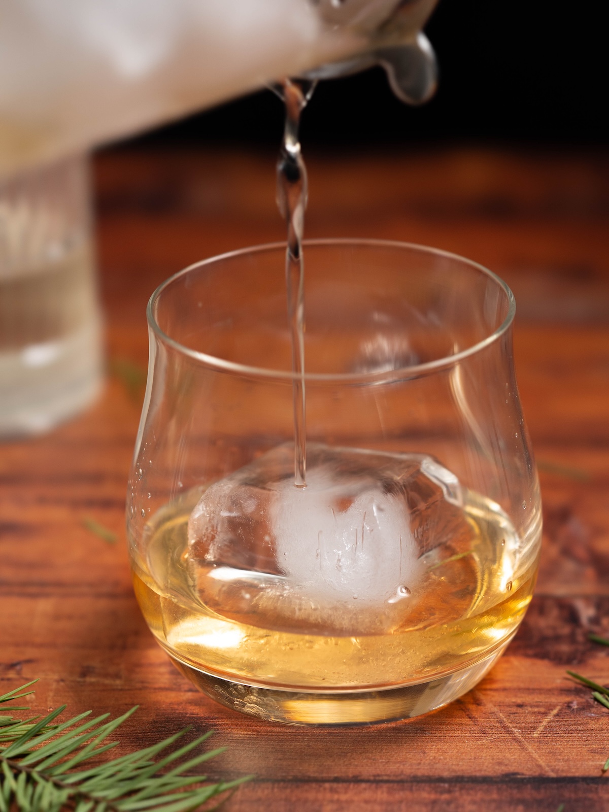 Straining a cocktail into a lowball glass over a big cube