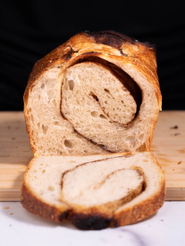 A loaf of cinnamon sugar sourdough bread, sliced to show cinnamon swirl inside