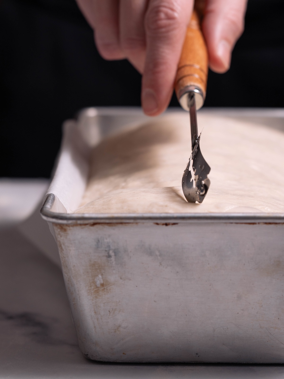 Scoring a loaf of bread with a bread lame