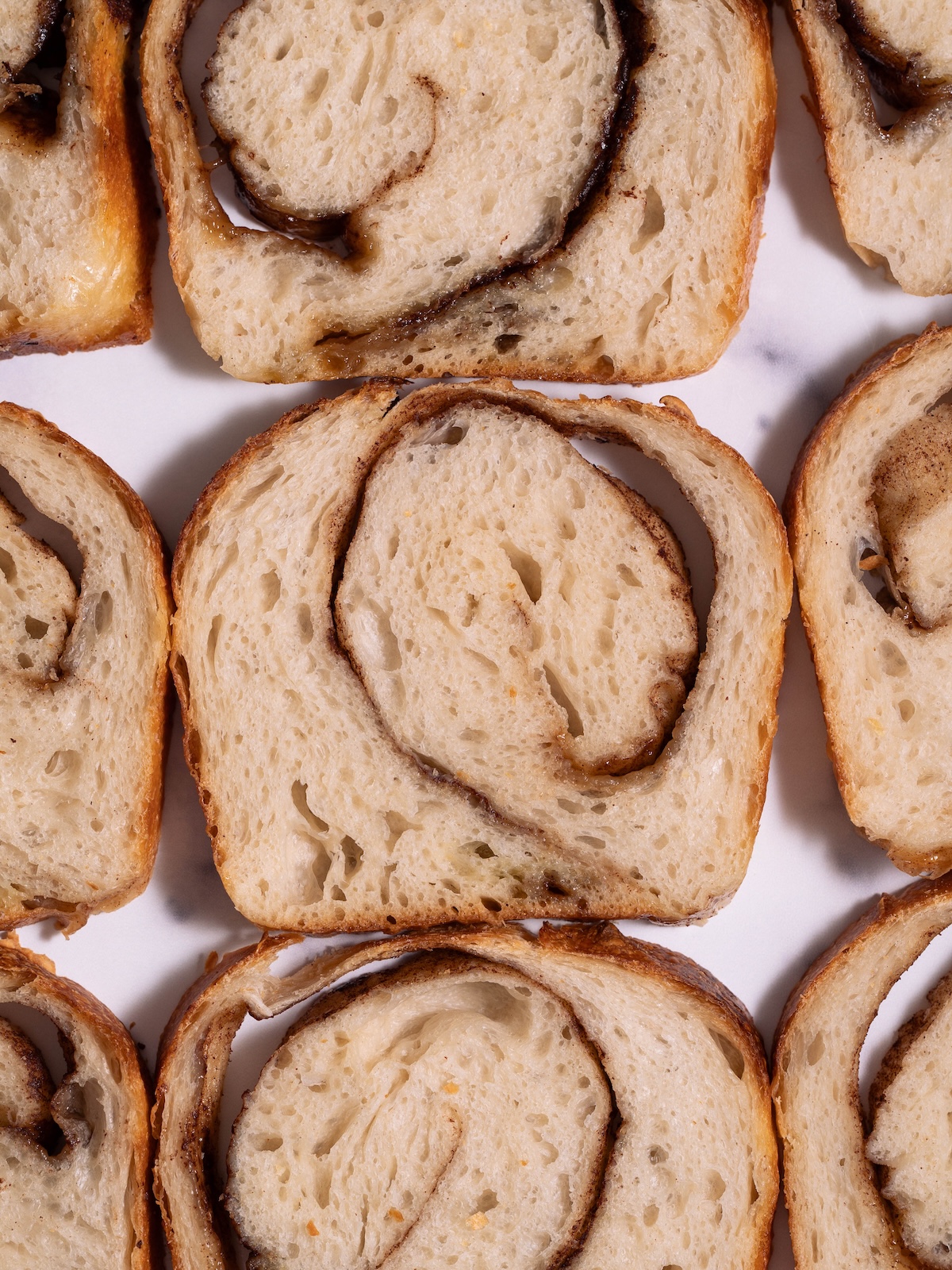 Slices of cinnamon swirl sourdough bread laid flat on a marble counter top