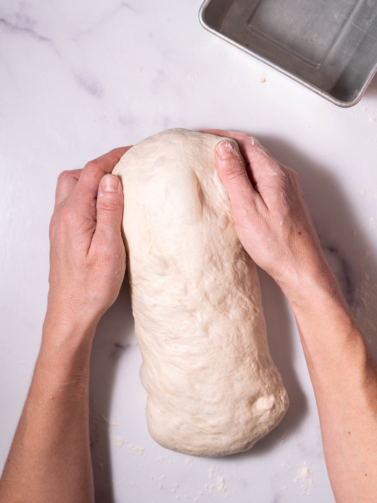 Tucking the ends under a loaf of bread dough to shape it
