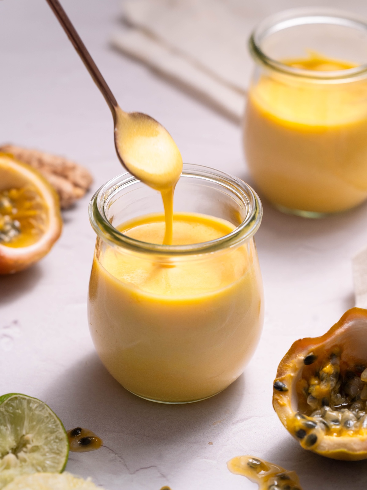 Passionfruit curd dripping off a spoon into a jar