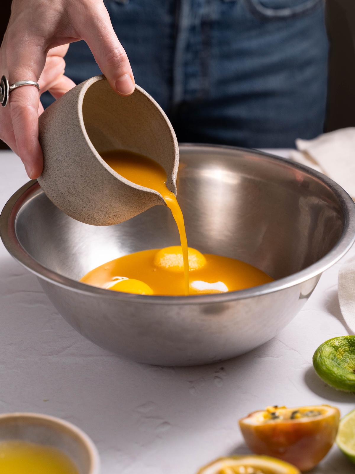 Pouring passionfruit puree into a bowl with other ingredients