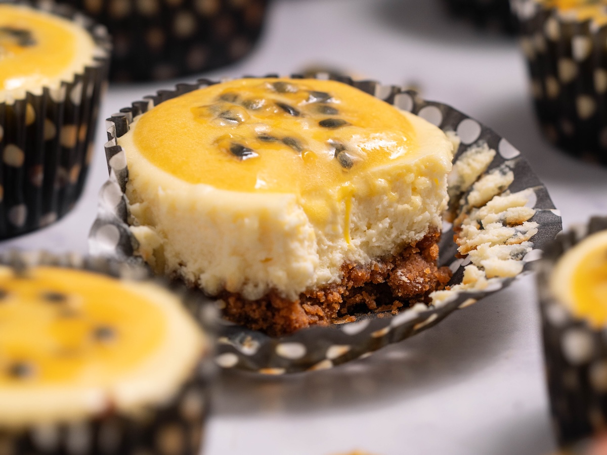 An individual passionfruit cheesecake with a bite taken out