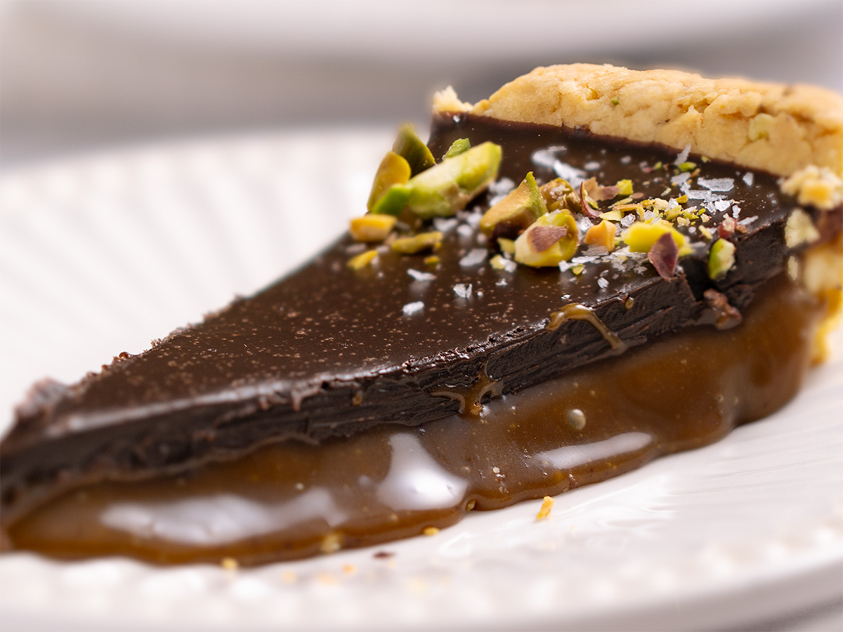 A closeup look at a gooey slice of pistachio caramel tart