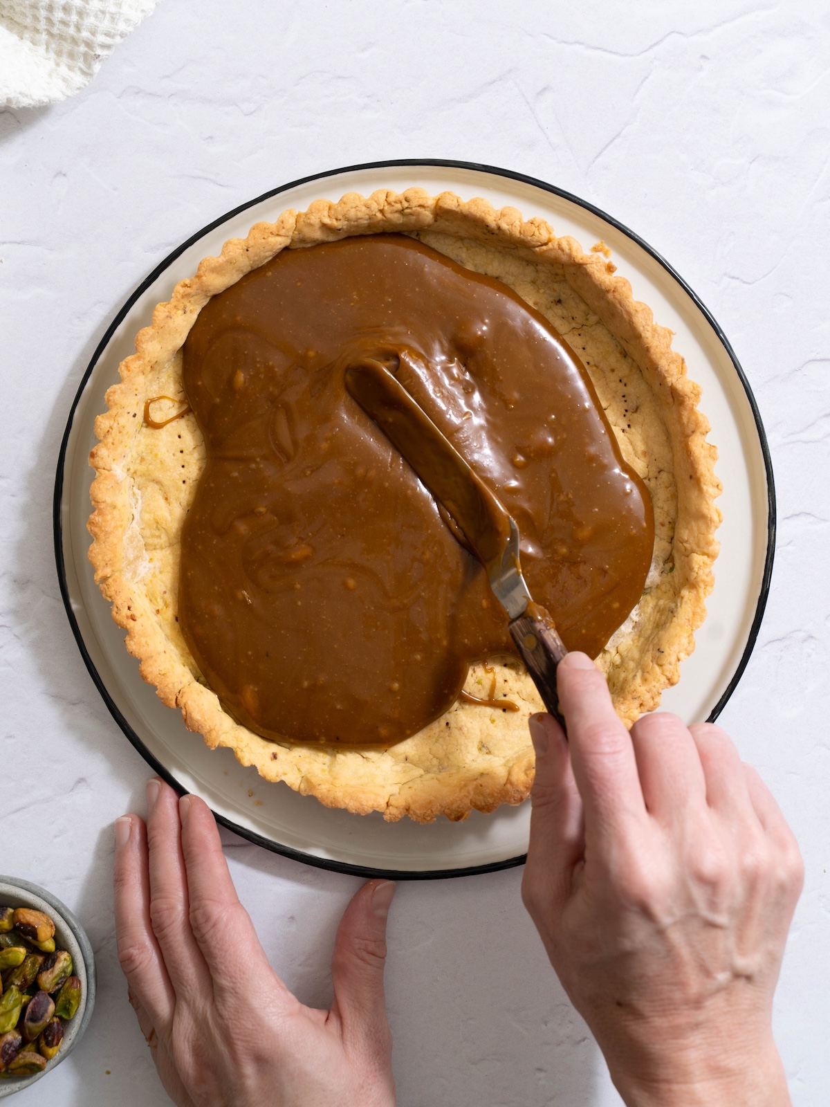 Spreading pistachio caramel into a baked tart crust