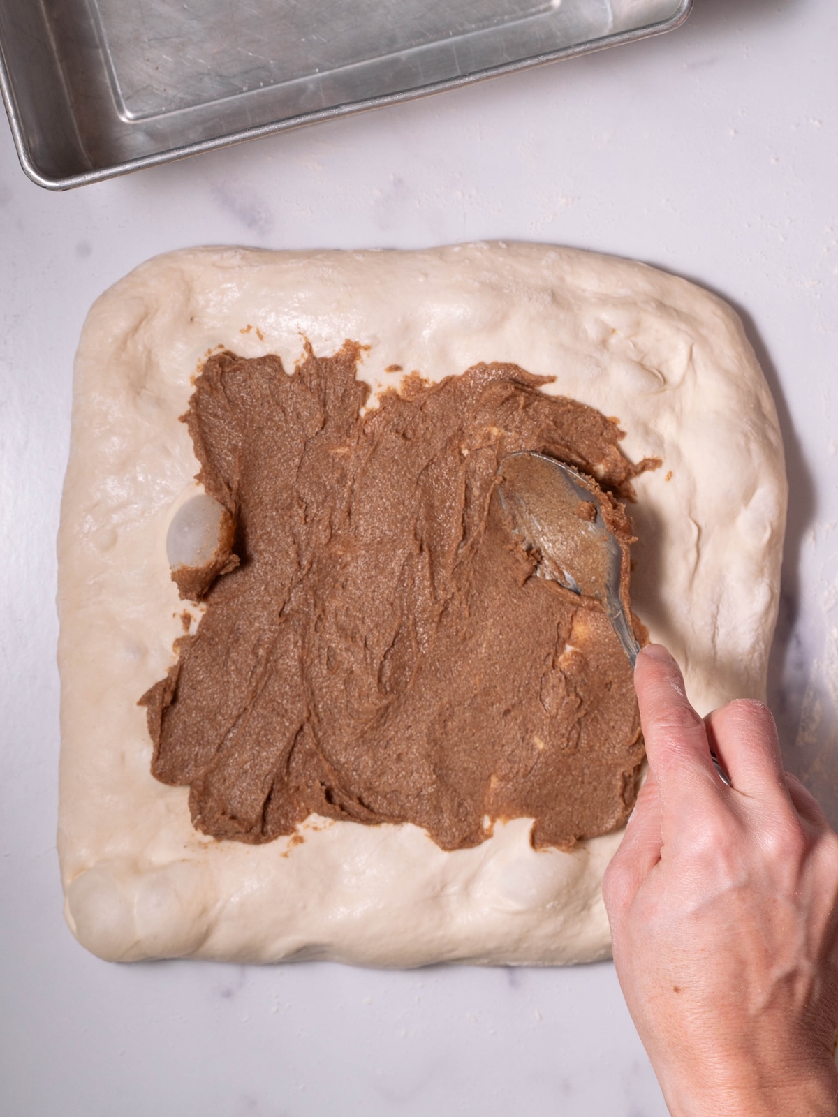 Spreading cinnamon butter on a rectangle of sourdough before shaping into a log