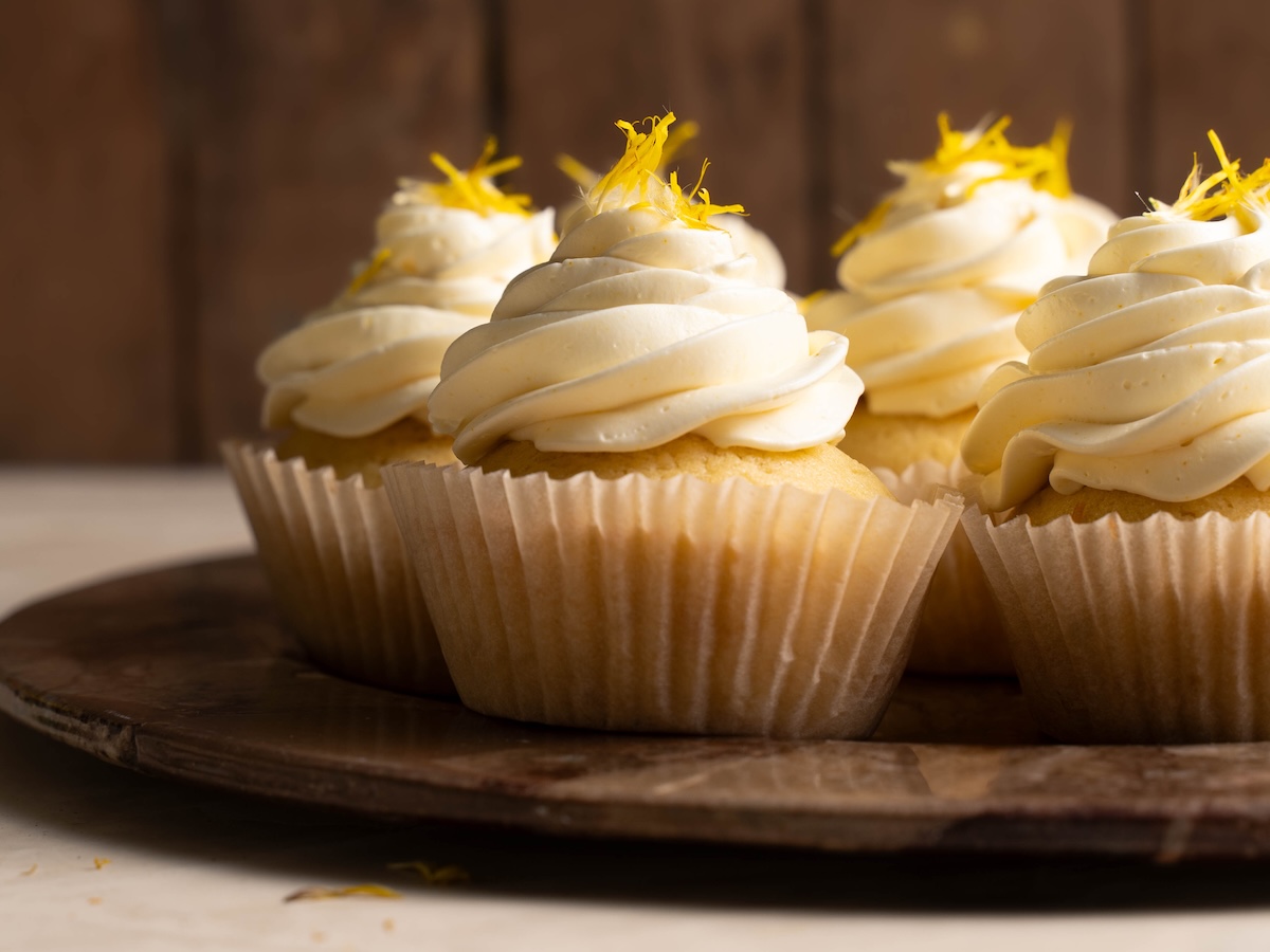 Yellow cupcakes decorated with Italian meringue buttercream and fresh flowers
