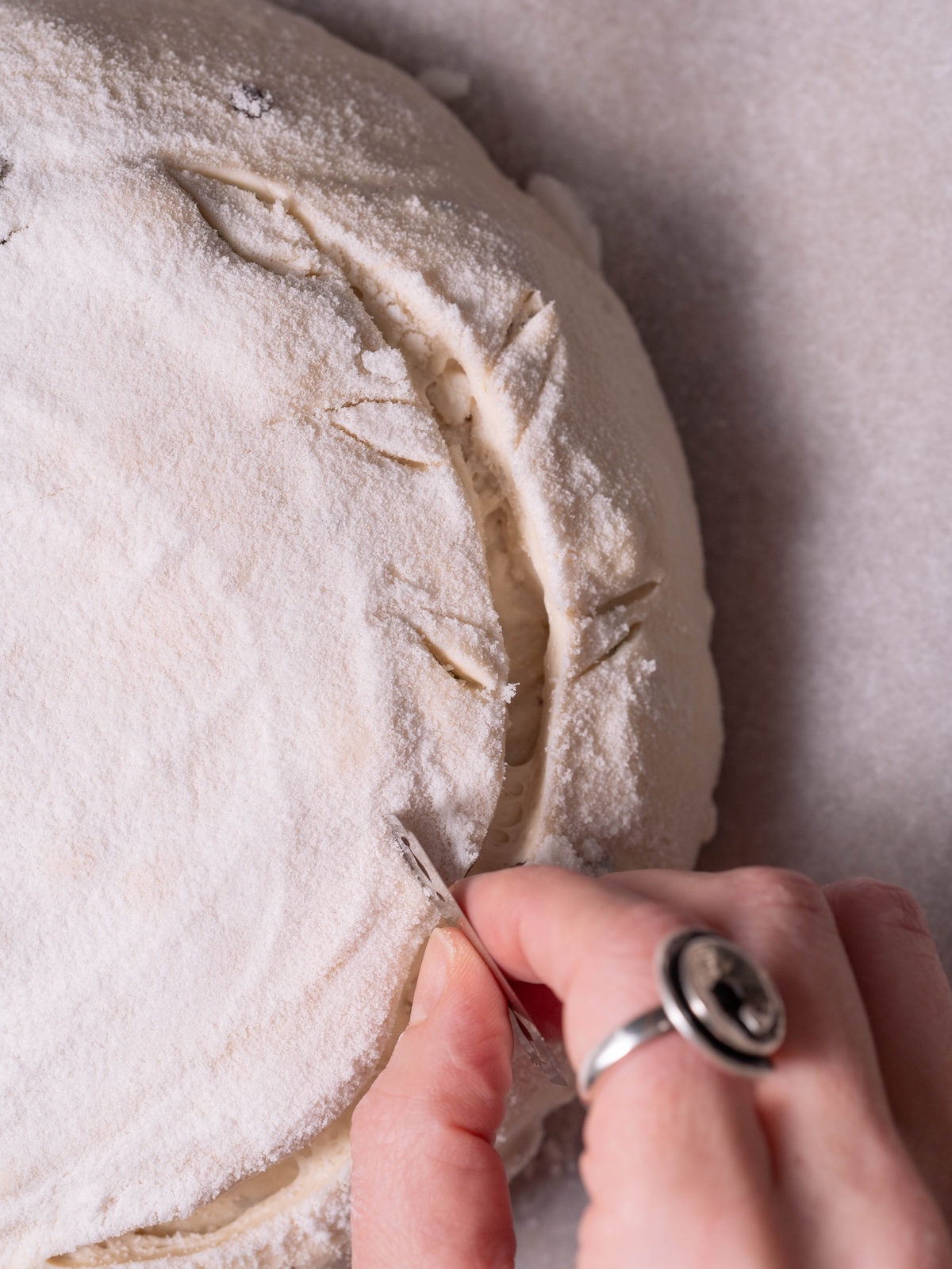 Scoring sourdough with an olive branch pattern