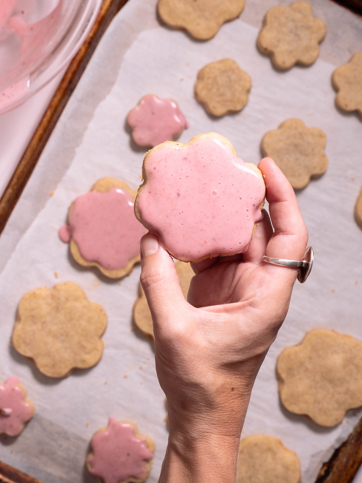 Hand holding a dipped glazed shortbread cookie