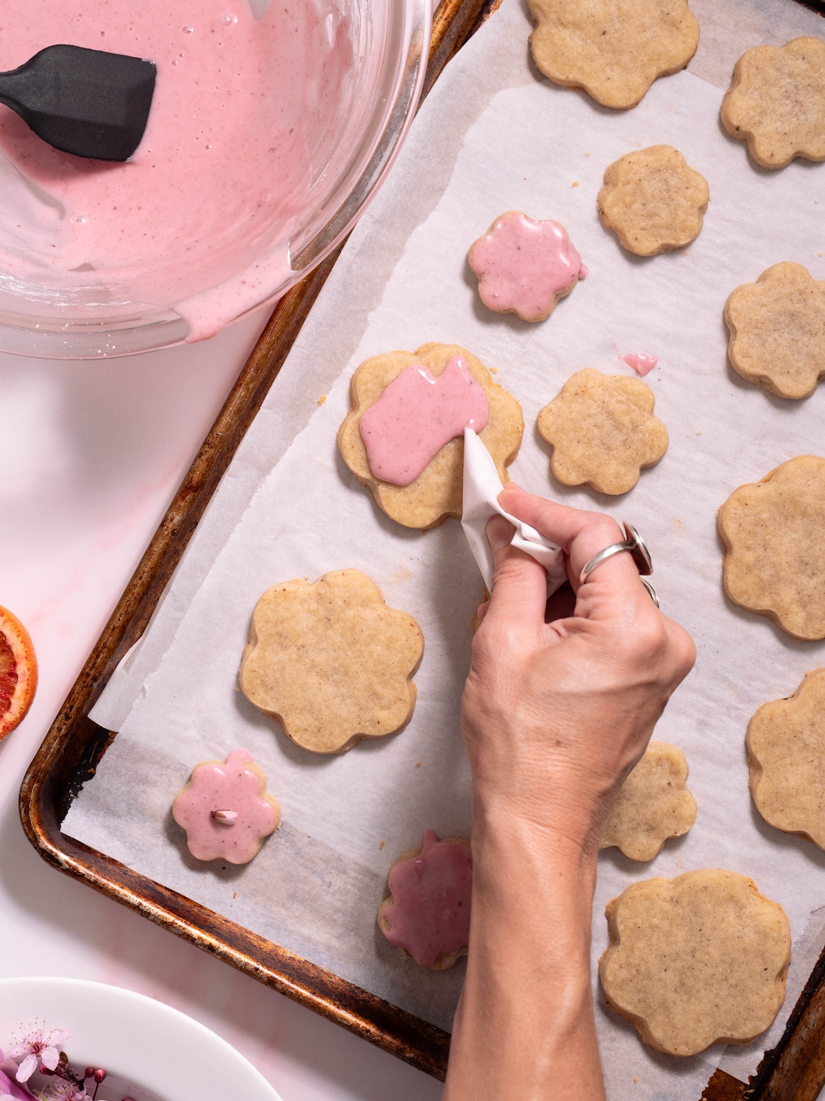 Drizzling blood orange glaze on a magnolia cookie