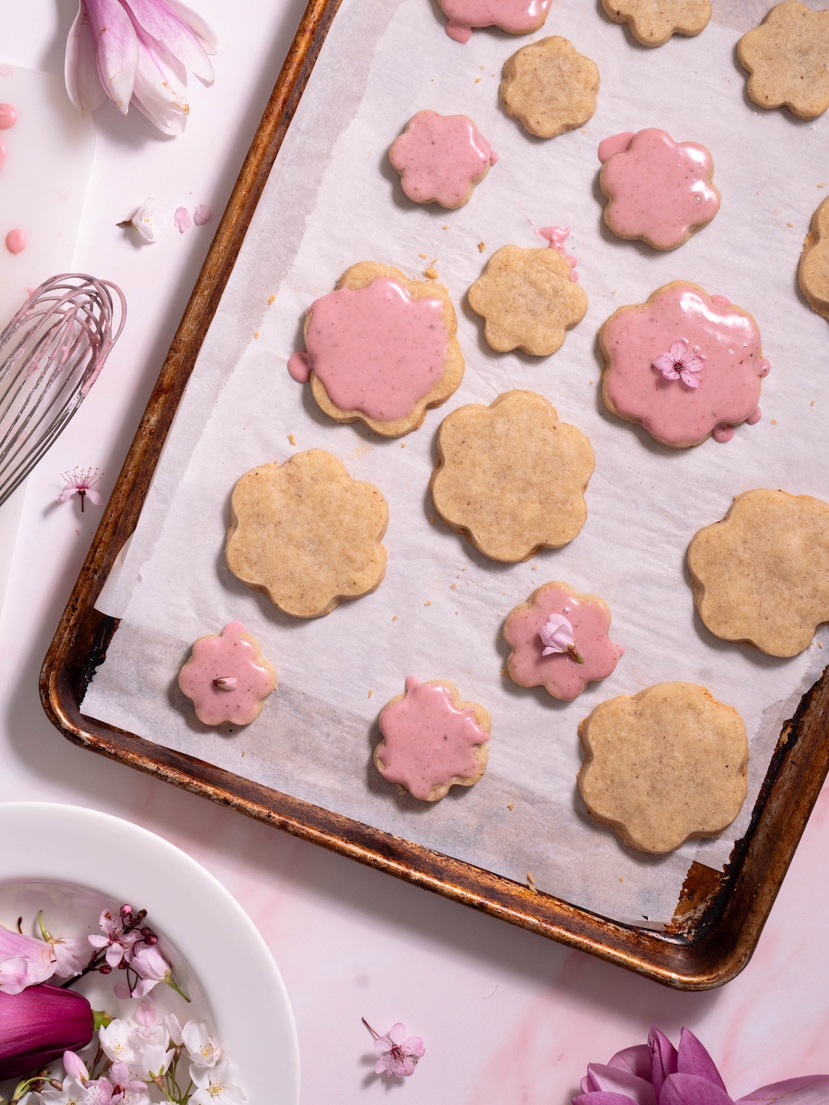 Magnolia shortbread cookies on a baking sheet surrounded by edible flowers