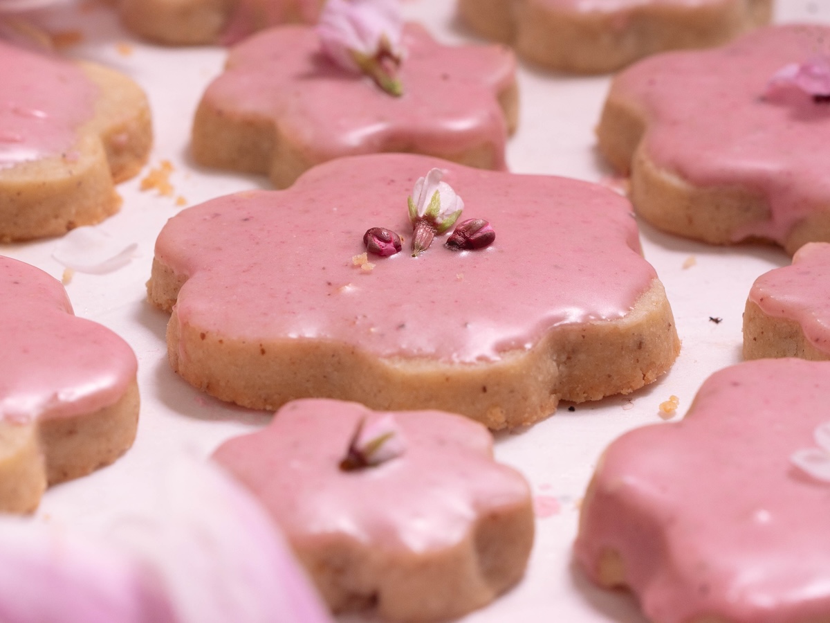 Side view of a glazed shortbread cookie with edible flowers on top