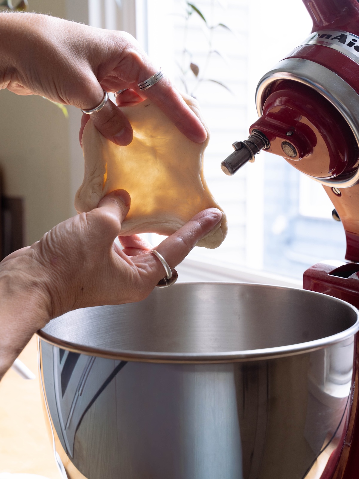 Stretching dough to see if it passes the windowpane test