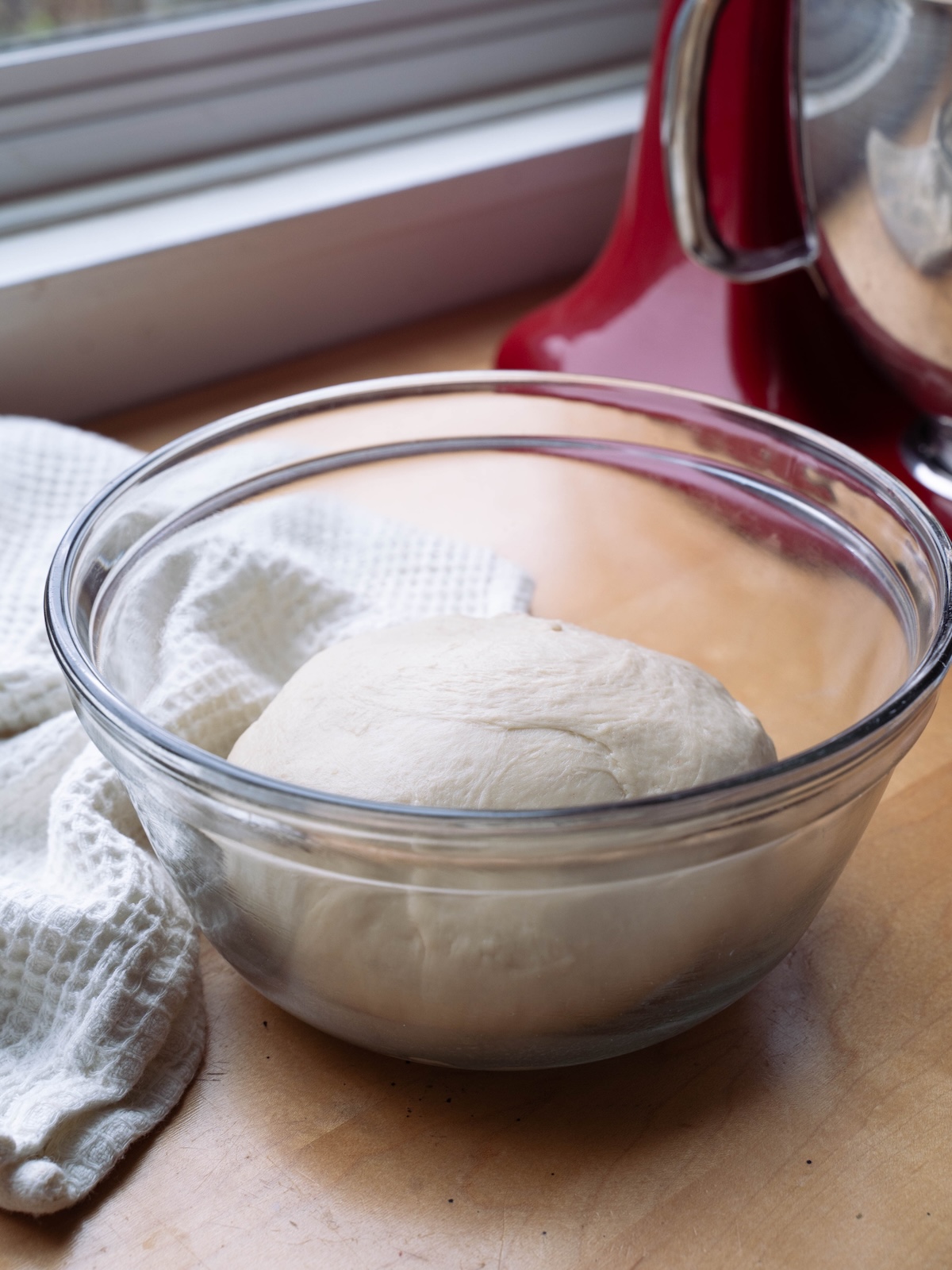 Bread dough in a bowl near a window