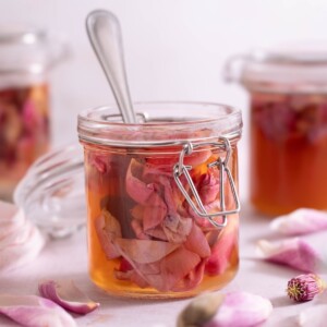 A jar of pickled magnolia petals with fresh magnolia flowers around it