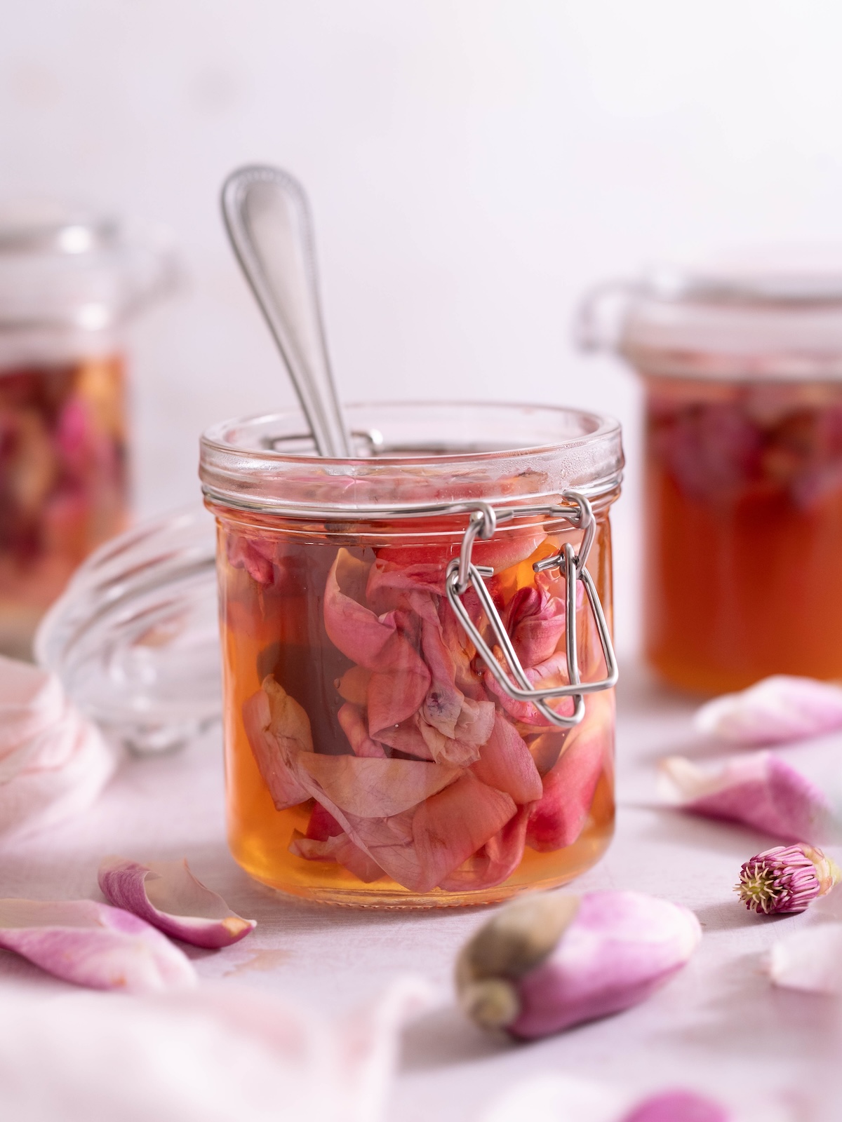 A jar of pickled magnolia petals with fresh magnolia flowers around it