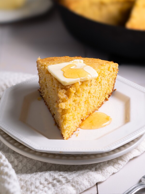 Sourdough cornbread sliced on a plate, topped with butter and honey