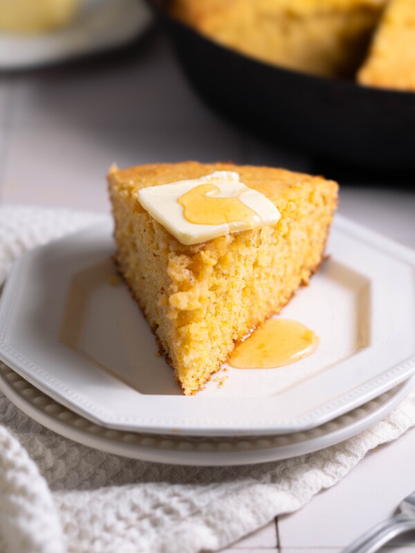 A slice of sourdough discard cornbread with butter and honey on top