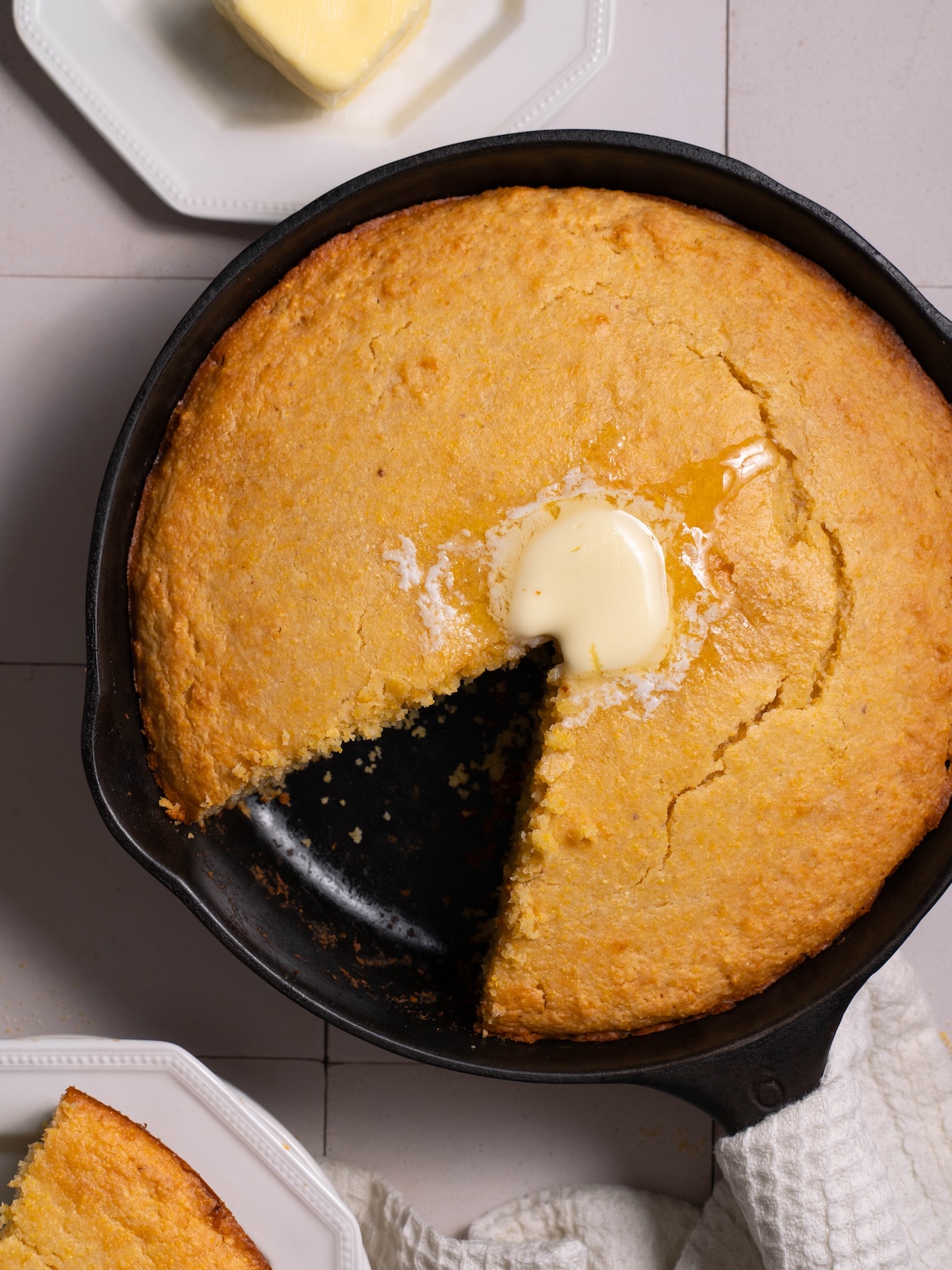 A batch of cornbread baked in a cast iron pan with melted butter on top