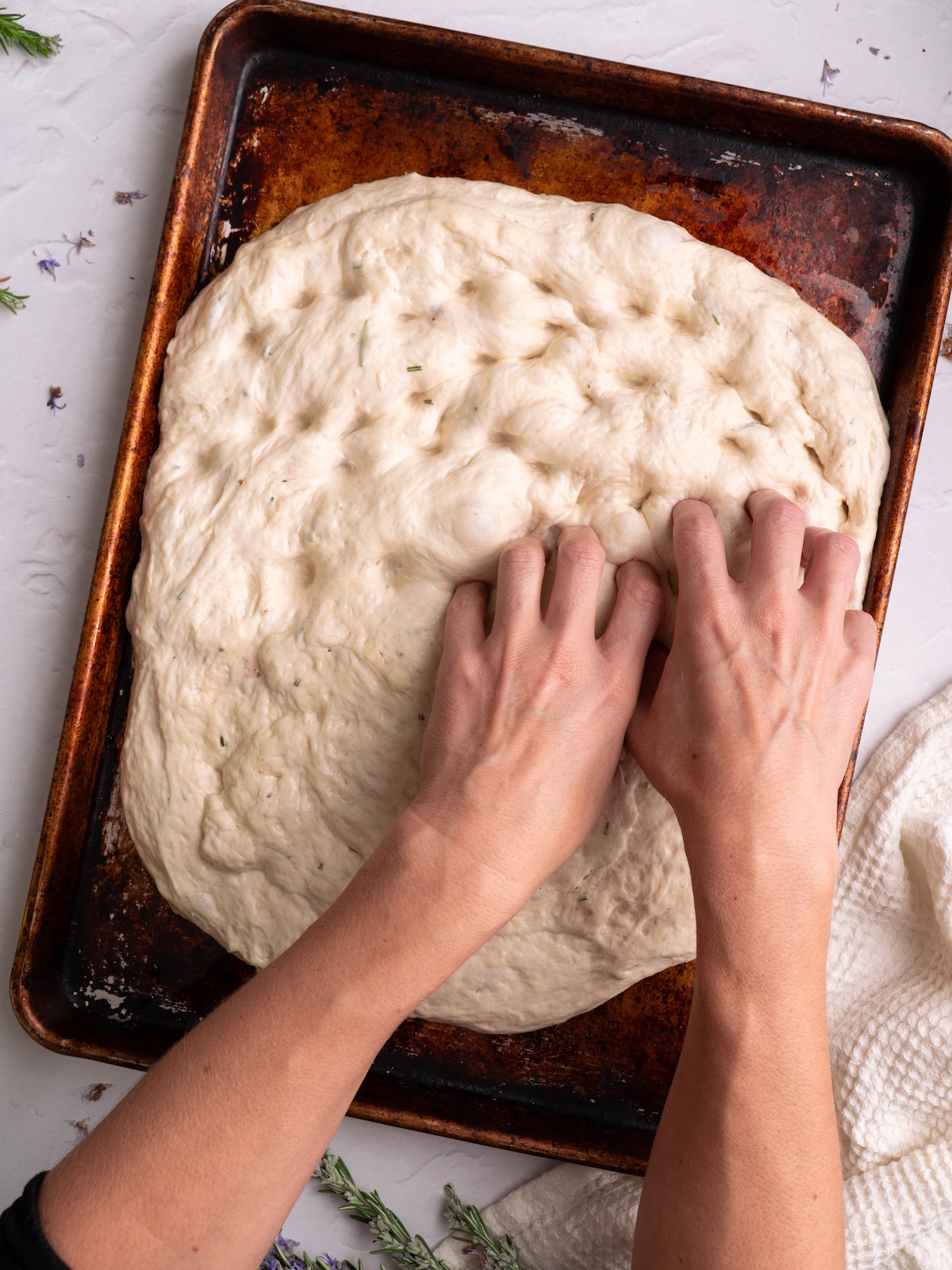 Dimpling focaccia dough with fingers