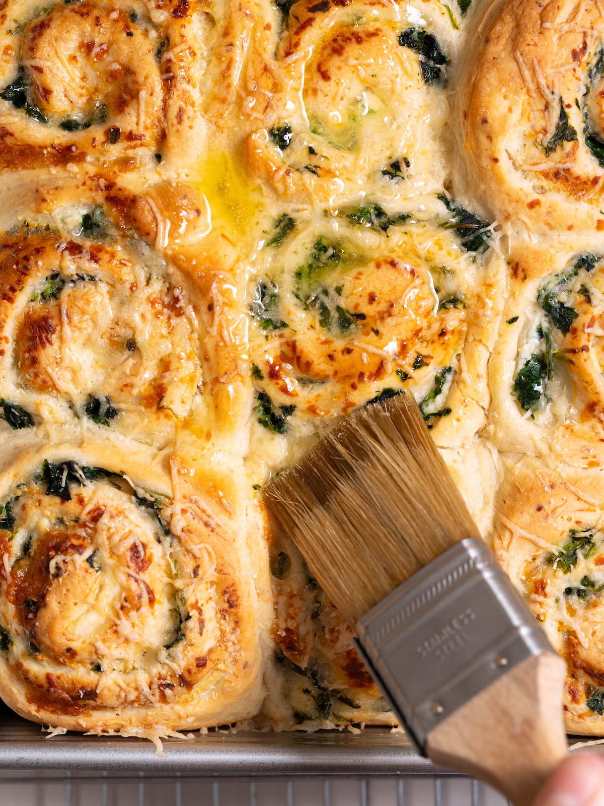 Brushing garlic butter onto savory cheesy rolls