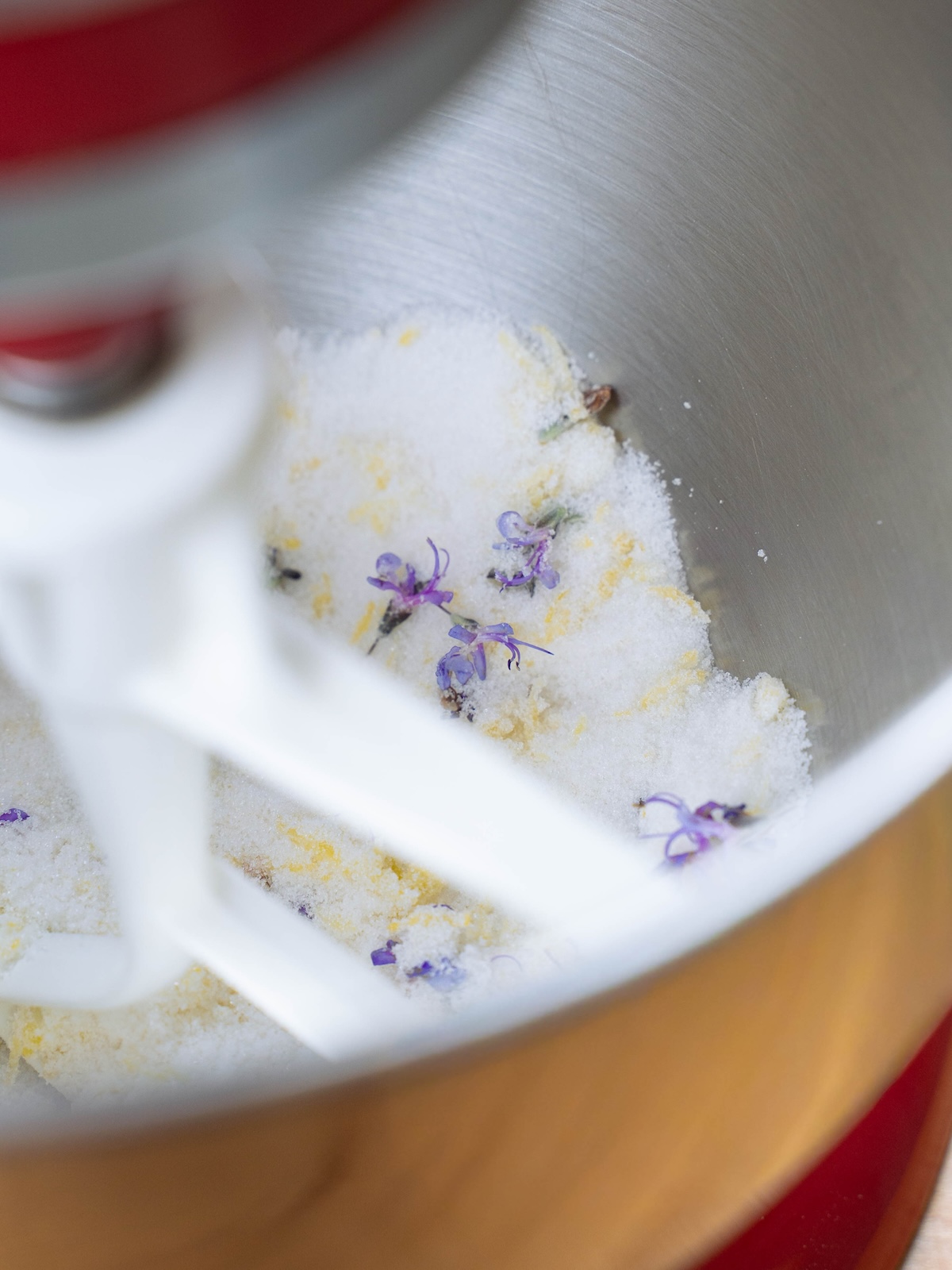 Lemon zest and rosemary flowers being mixed into sugar