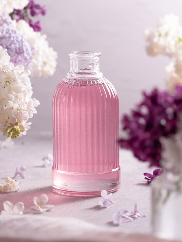 A small glass bottle filled with light purple lilac syrup