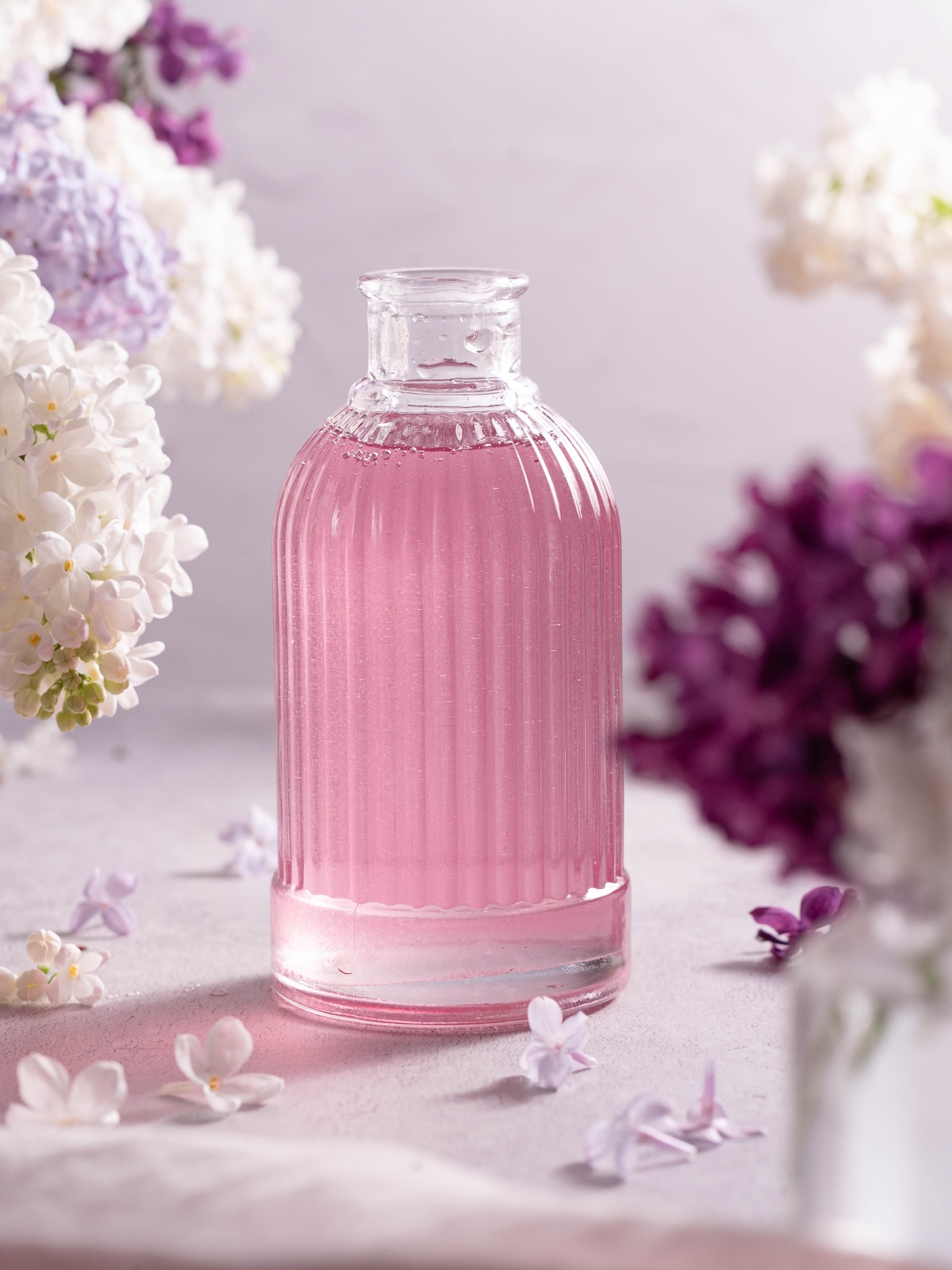 A small glass bottle filled with light purple lilac syrup