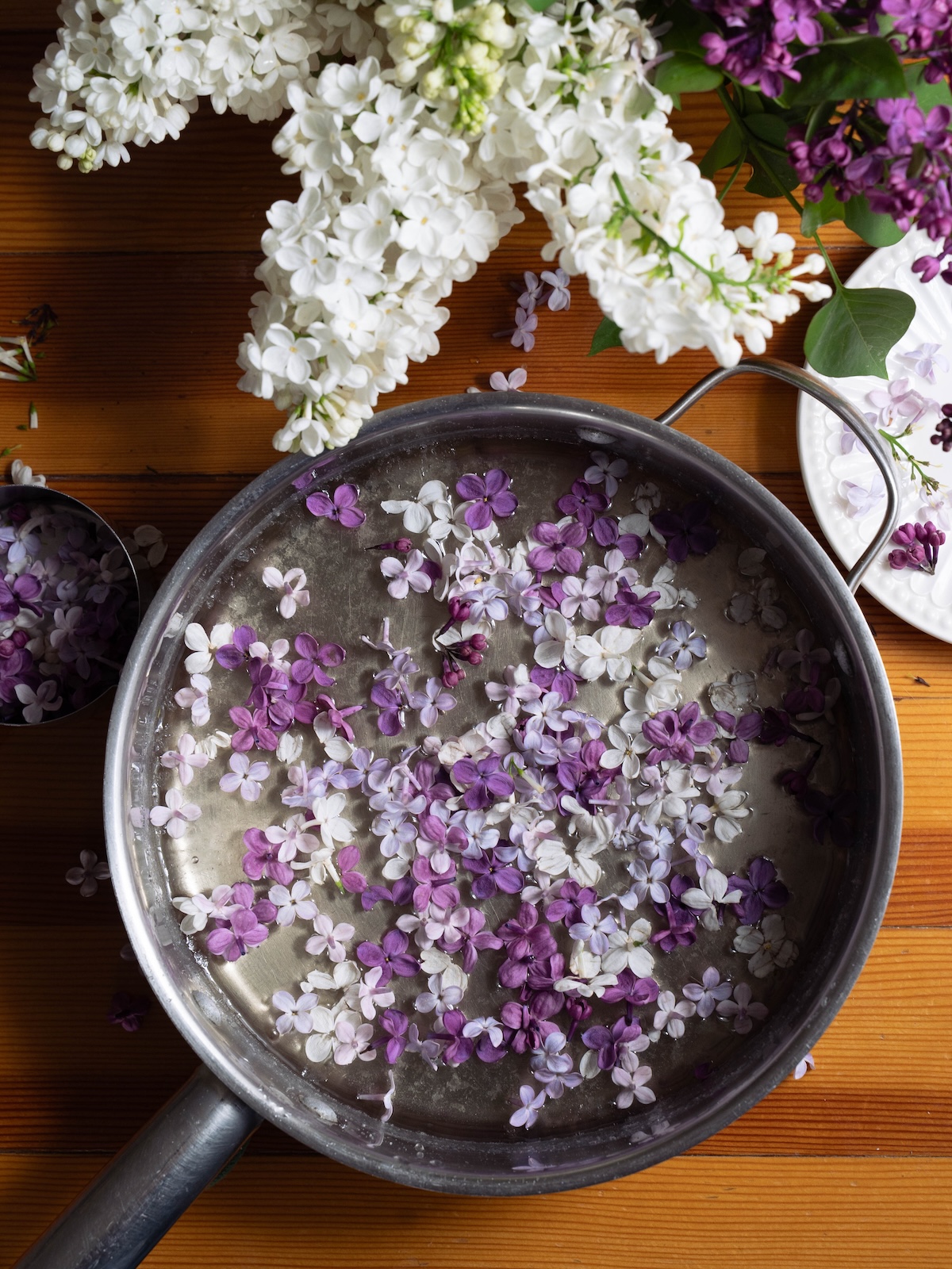 White and purple lilac flowers in a saucepan of simple syrup