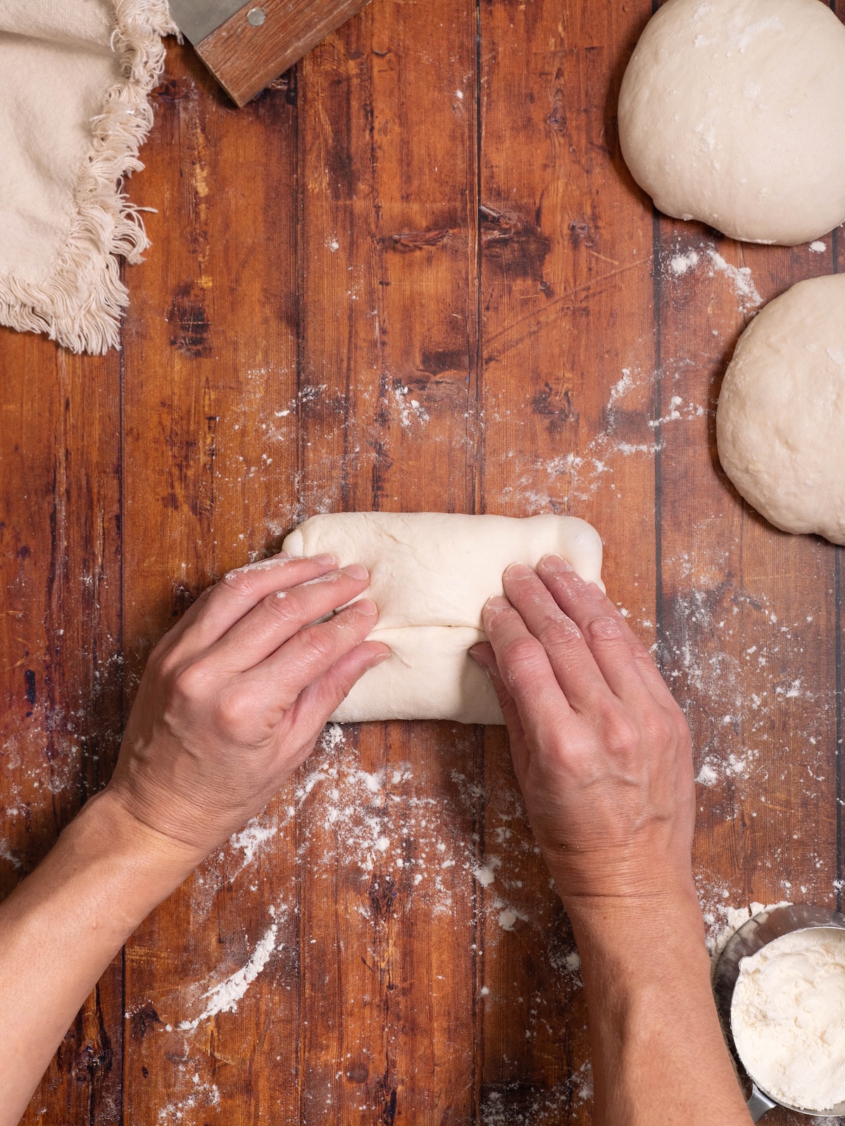Folding bread dough to shape into a baguette