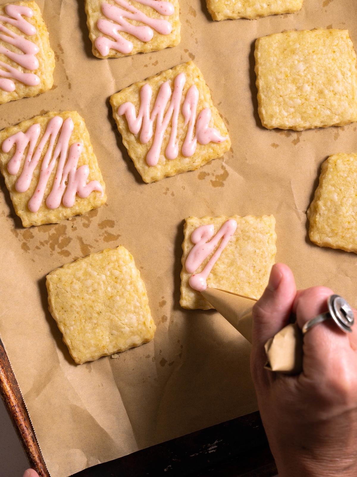 Piping strawberry glaze onto shortbread cookies
