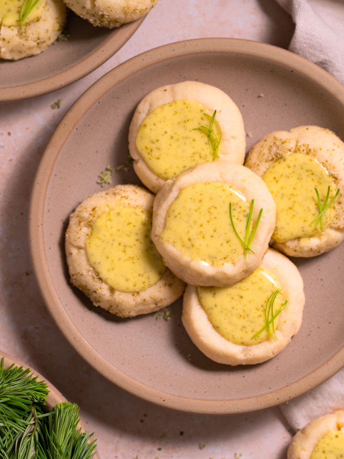 Lemon thumbprint cookies filled with lemon fir tip curd on a plate