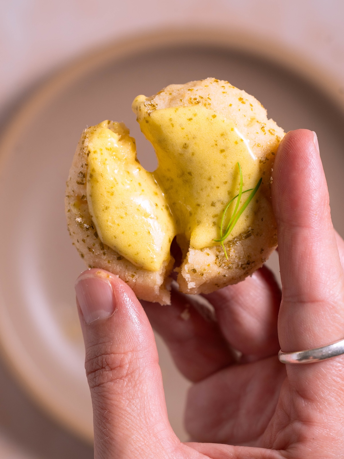 A thumbprint cookie breaking open, with curd spilling out