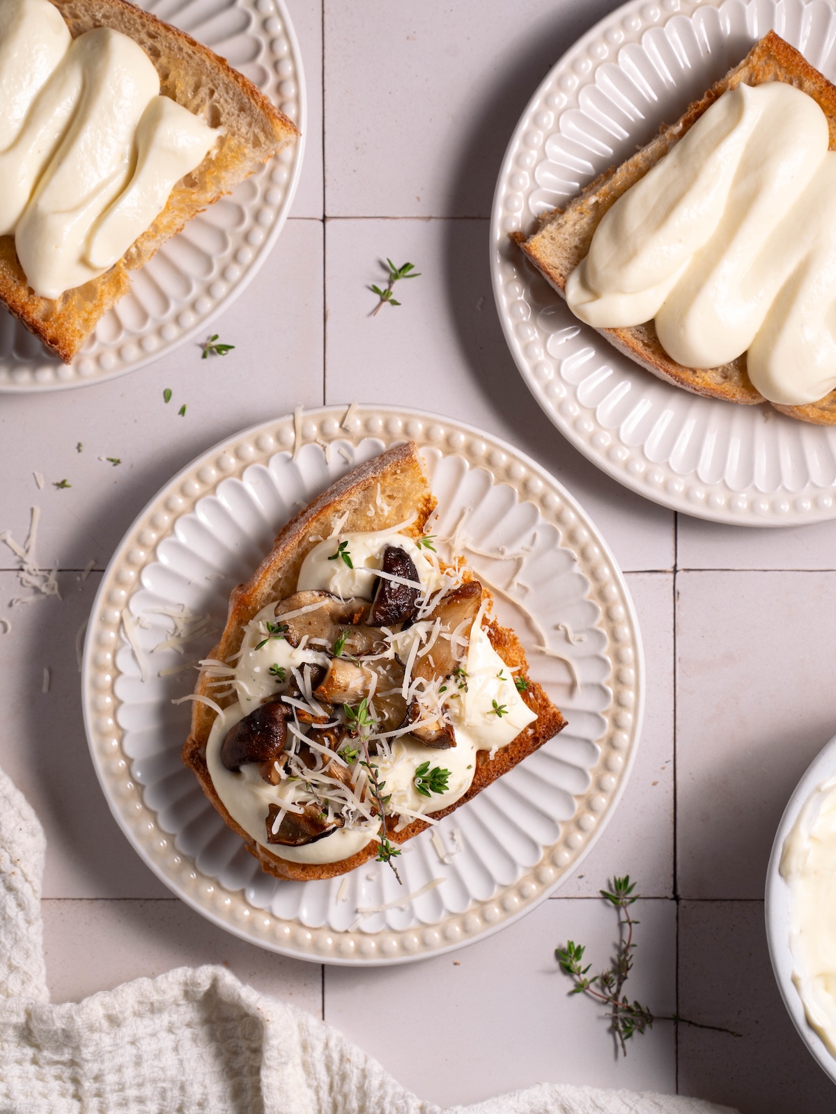Whipped ricotta mushroom toasts on white plates