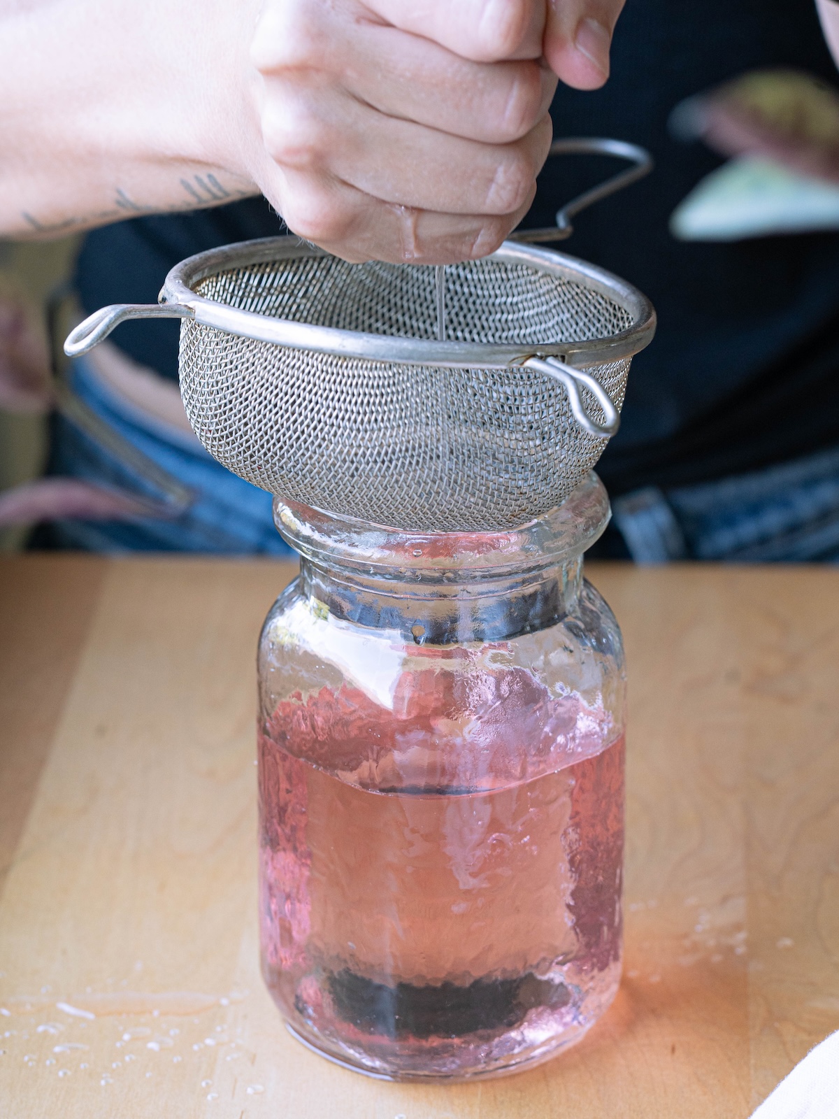 Squeezing simple syrup out of cheesecloth over a strainer