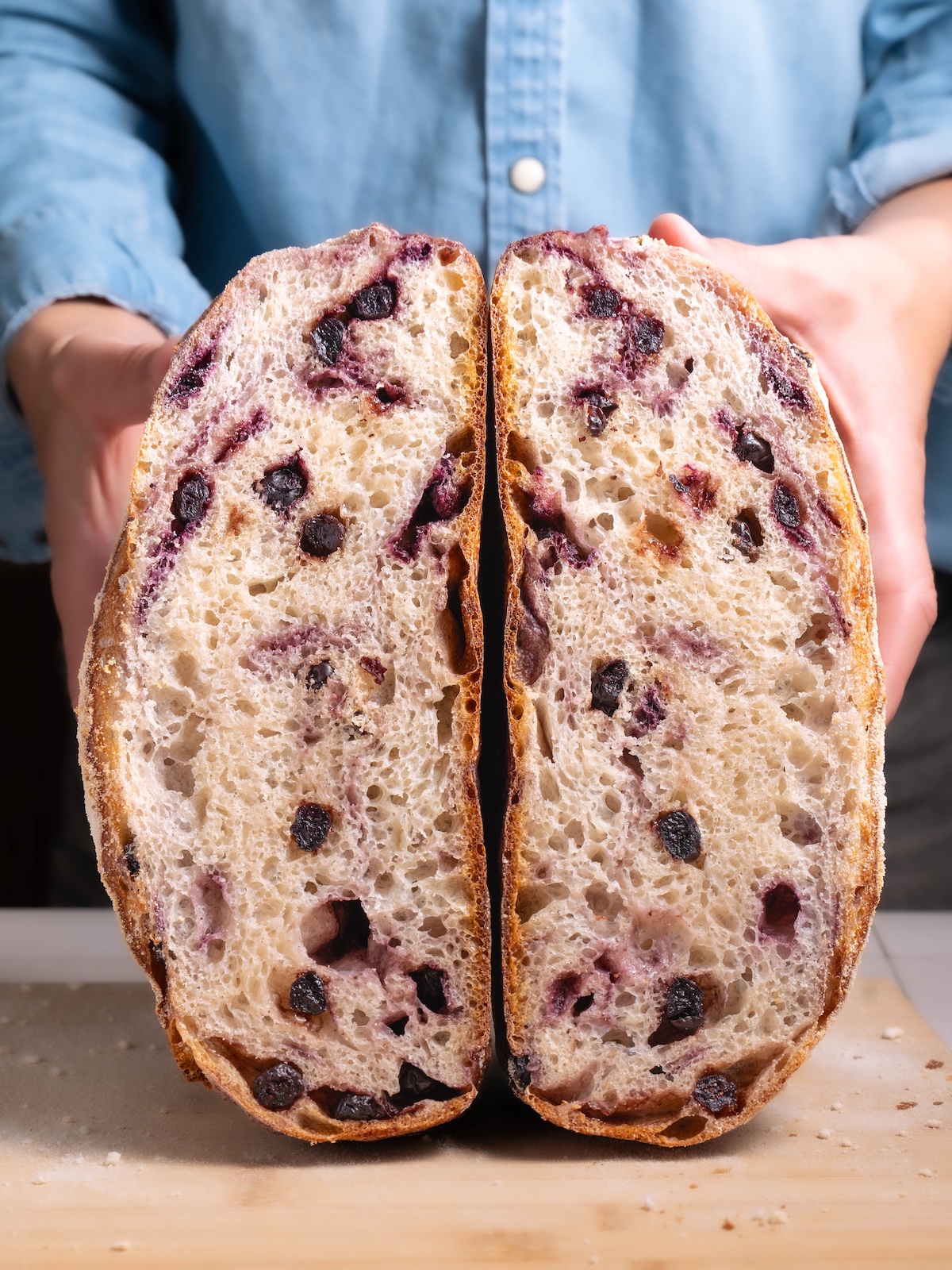 A loaf of blueberry sourdough bread sliced in half to show interior