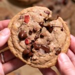 Hands breaking open a chocolate chip cookie filled with strawberries
