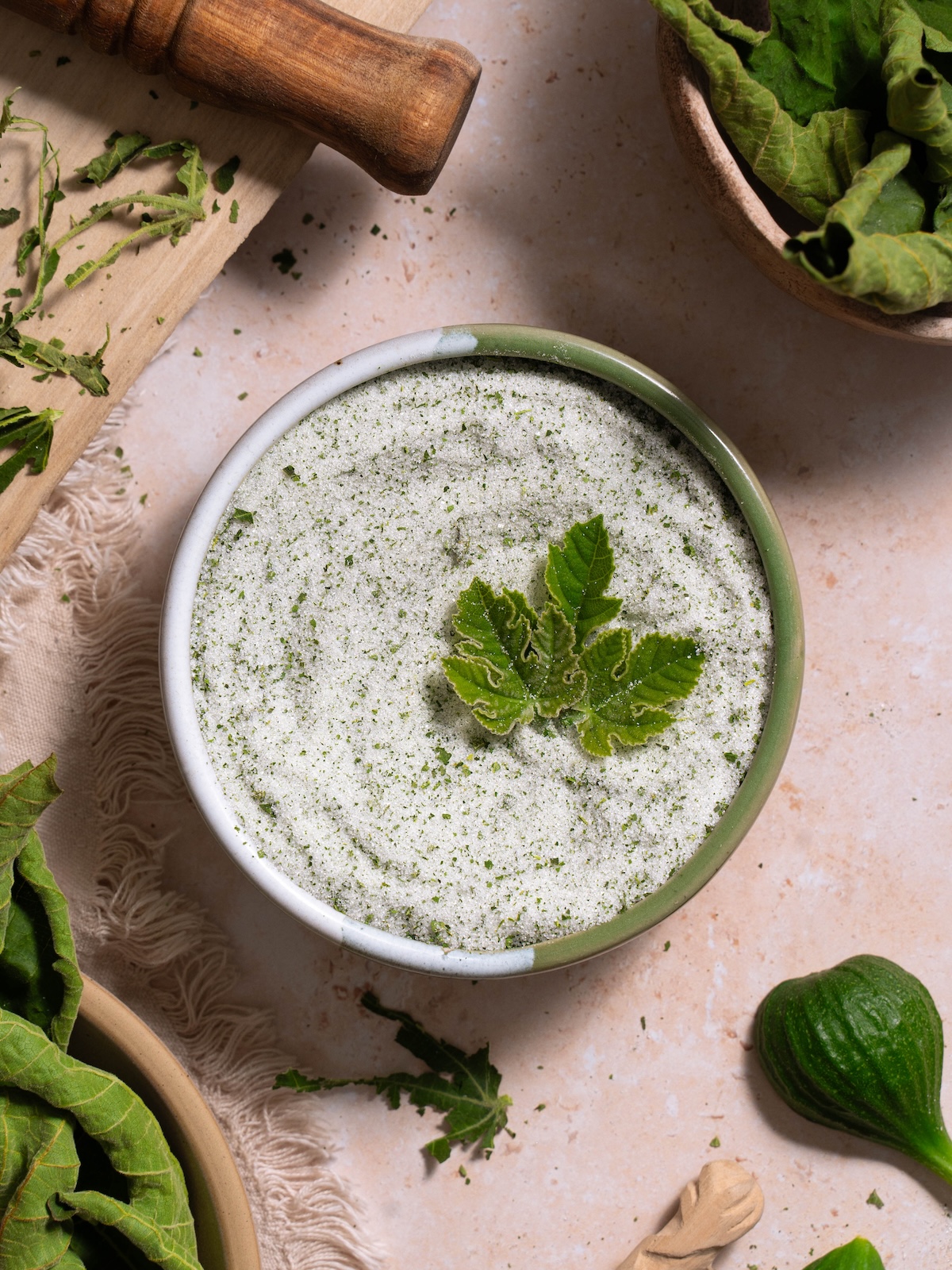 A bowl of toasted fig leaf sugar surrounded by toasted fig leaves