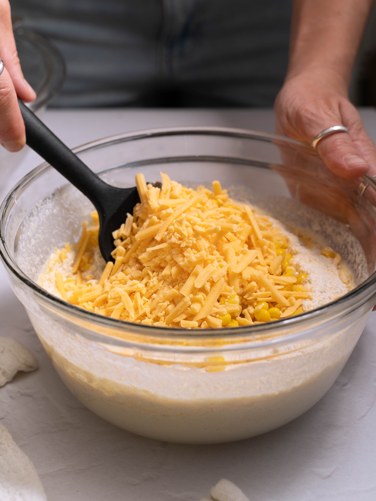Folding corn and shredded cheddar into muffin batter