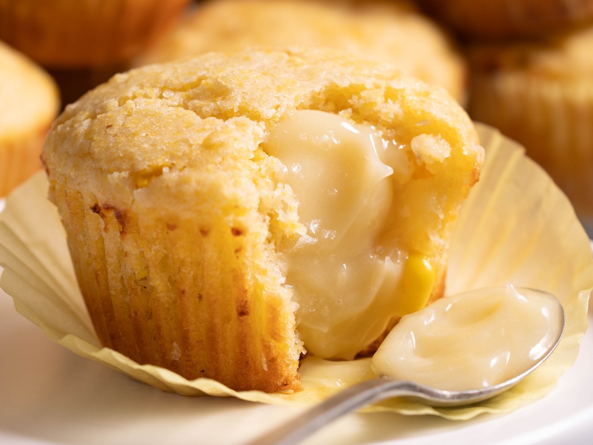 A closeup of a sourdough corn muffin spread with whipped honey butter