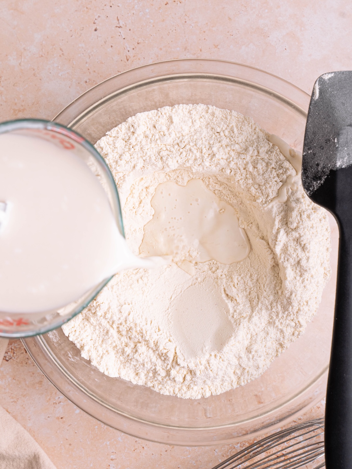 Pouring liquid ingredients into dry ingredients in a mixing bowl